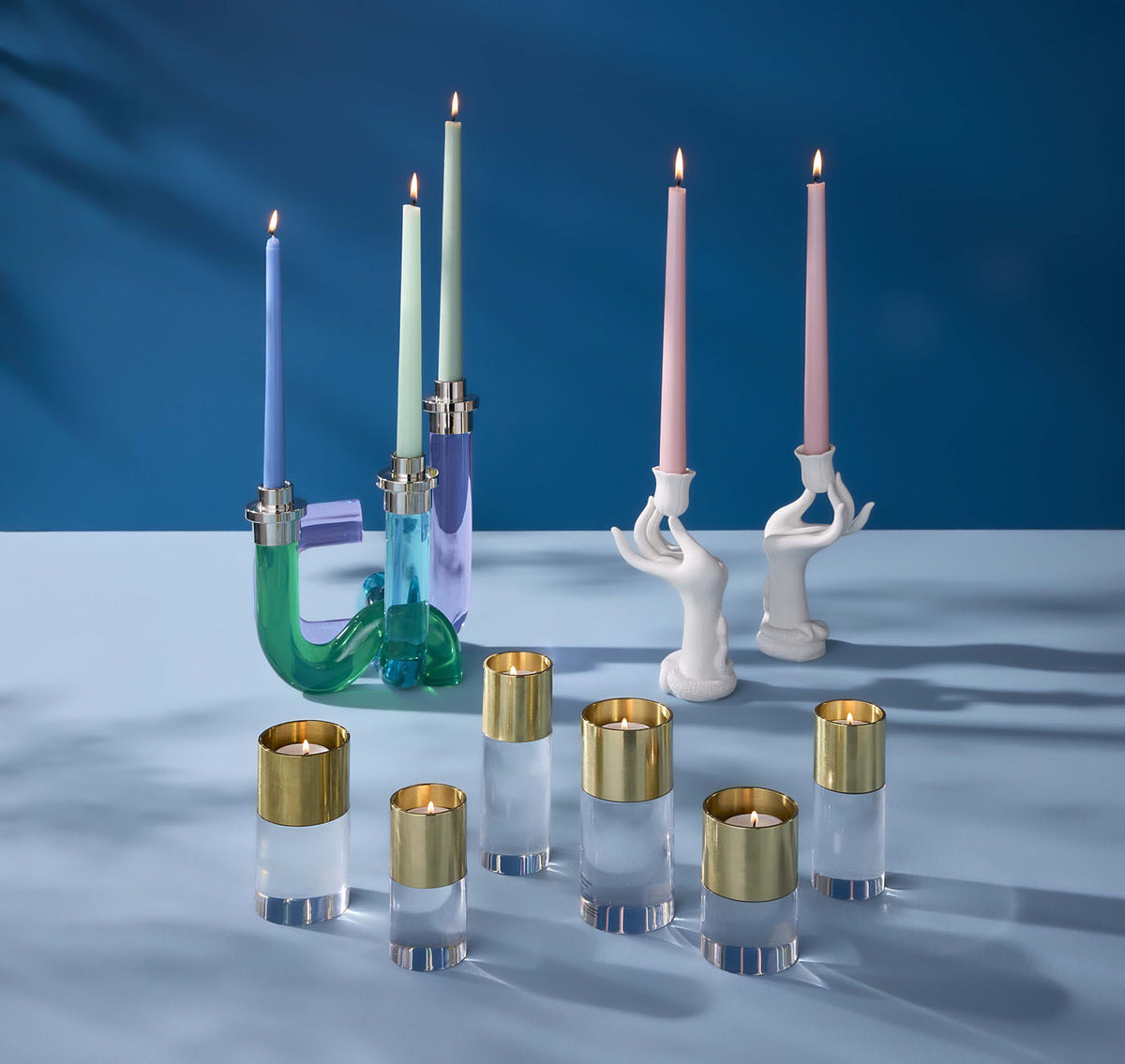 Collection of colorful candle holders and candles on a blue background
