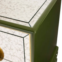 Close-up of a green door frame with glass panels on a white marble floor.