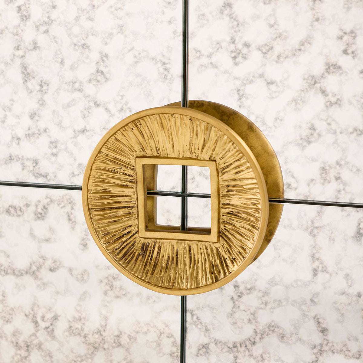 Gold circular light fixture with textured design on a marble wall background