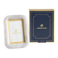 Marble photo frame with gold accents and Jonathan Adler packaging on a white background