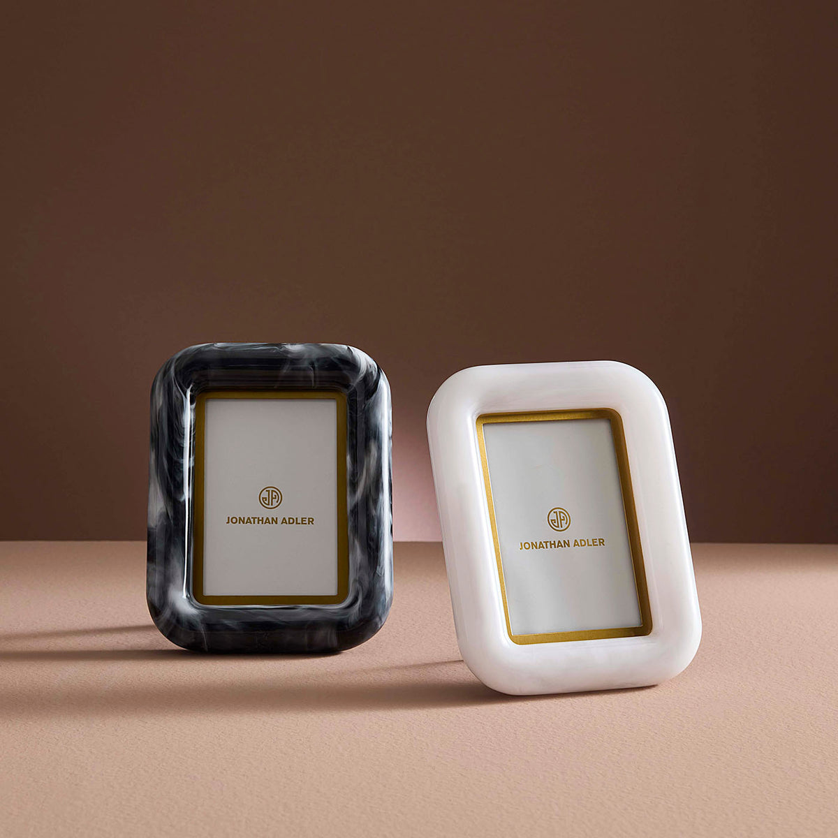 Two photo frames, one black and one white, with gold accents on a brown background.