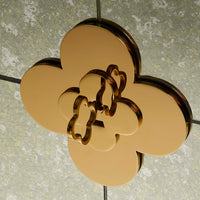 Gold-colored decorative object with a floral design on a textured gray background