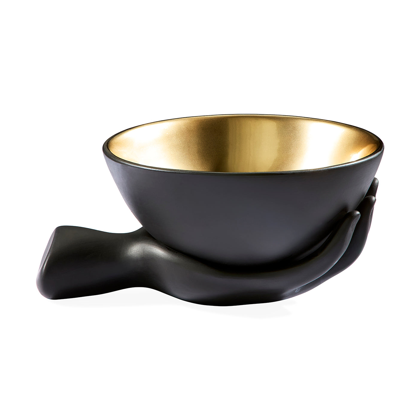 A black ceramic bowl with a metallic gold interior, shaped to rest in a sculptural hand-like base, shown on a plain white background.
