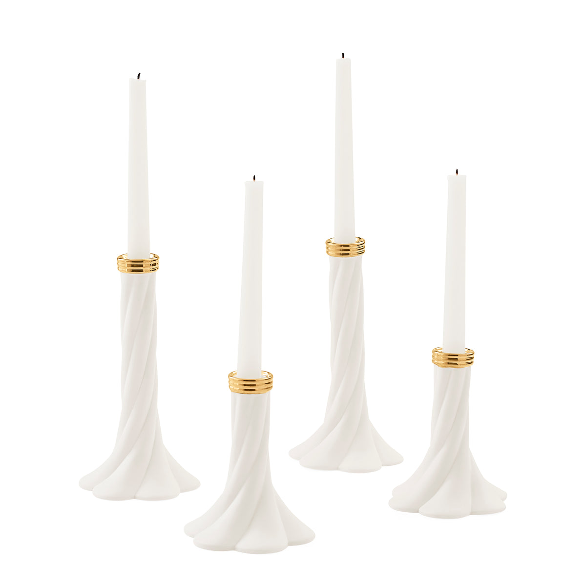 Four white tapered candles in sculptural flared holders with gold bands, arranged on a clean white background.
