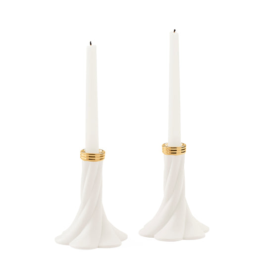 A pair of white taper candle holders with a flared, sculptural base and gold metallic bands near the top, shown on a plain white background.