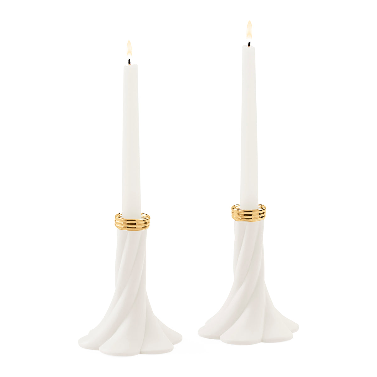 Two white taper candles in sculptural flared holders with gold bands, shown on a plain white background.
