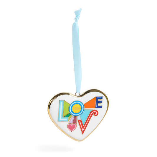 A heart-shaped hanging ornament with a gold-toned border, a white center, and the word LOVE spelled out in colorful geometric shapes. A light blue ribbon is tied to the top for hanging.
