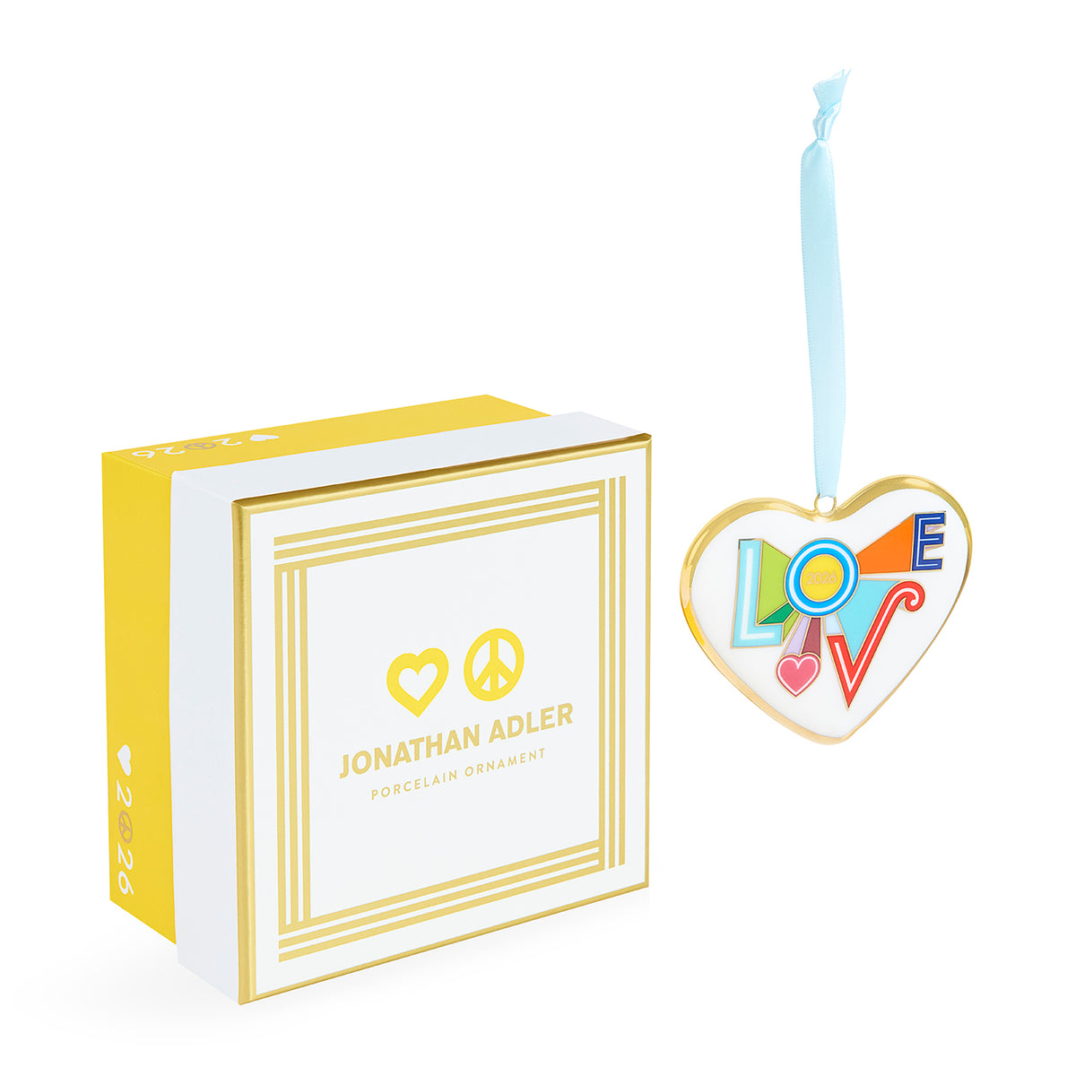 Jonathan Adler porcelain ornament featuring the word LOVE in colorful letters inside a heart outline, shown next to its white and yellow gift box on a white background.