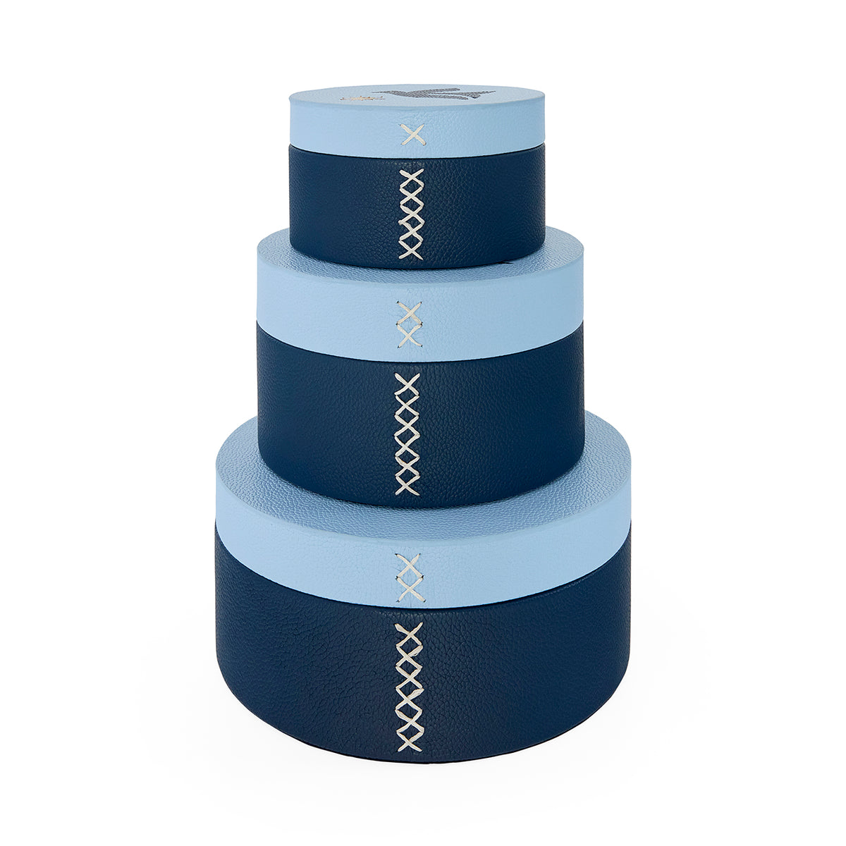Set of four navy and light blue cylindrical boxes with decorative stitching on a white background