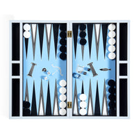 A fully set up backgamol with a light blue playing field, black and white checkers, and various game pieces arranged symmetrically inside an open white wooden case.