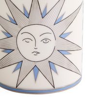 Close-up of a white ceramic vase featuring a stylized sun face with closed and open eyes, outlined in black, with light blue accents in the starburst rays.