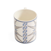 A white ceramic mug with a blue and gray geometric pattern, shown from a three-quarters perspective on a white background.