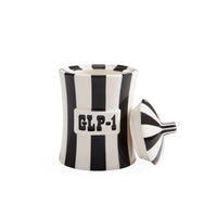 A white ceramic container with bold black vertical stripes and a matching lid leaning against it, featuring a white label with black text reading 'GLP-1'.