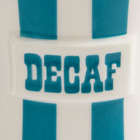 Close-up of a white cylindrical product with blue vertical stripes and the word 'DECAF' in raised blue letters across the center.